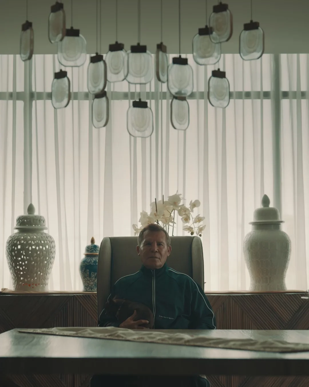 BOXRAW campaign still: a seated figure between tall white vases