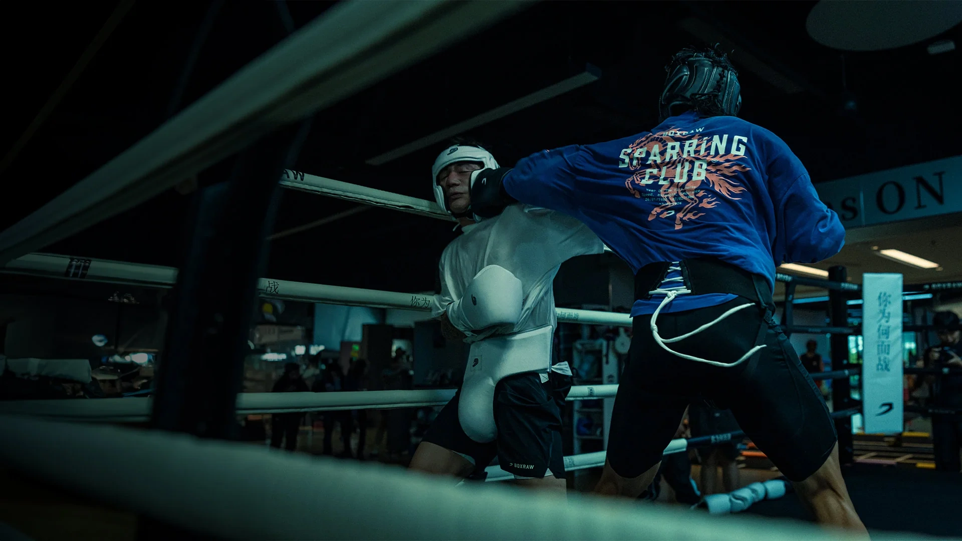 Two fighters in a ring, one in a blue Sparring Club top