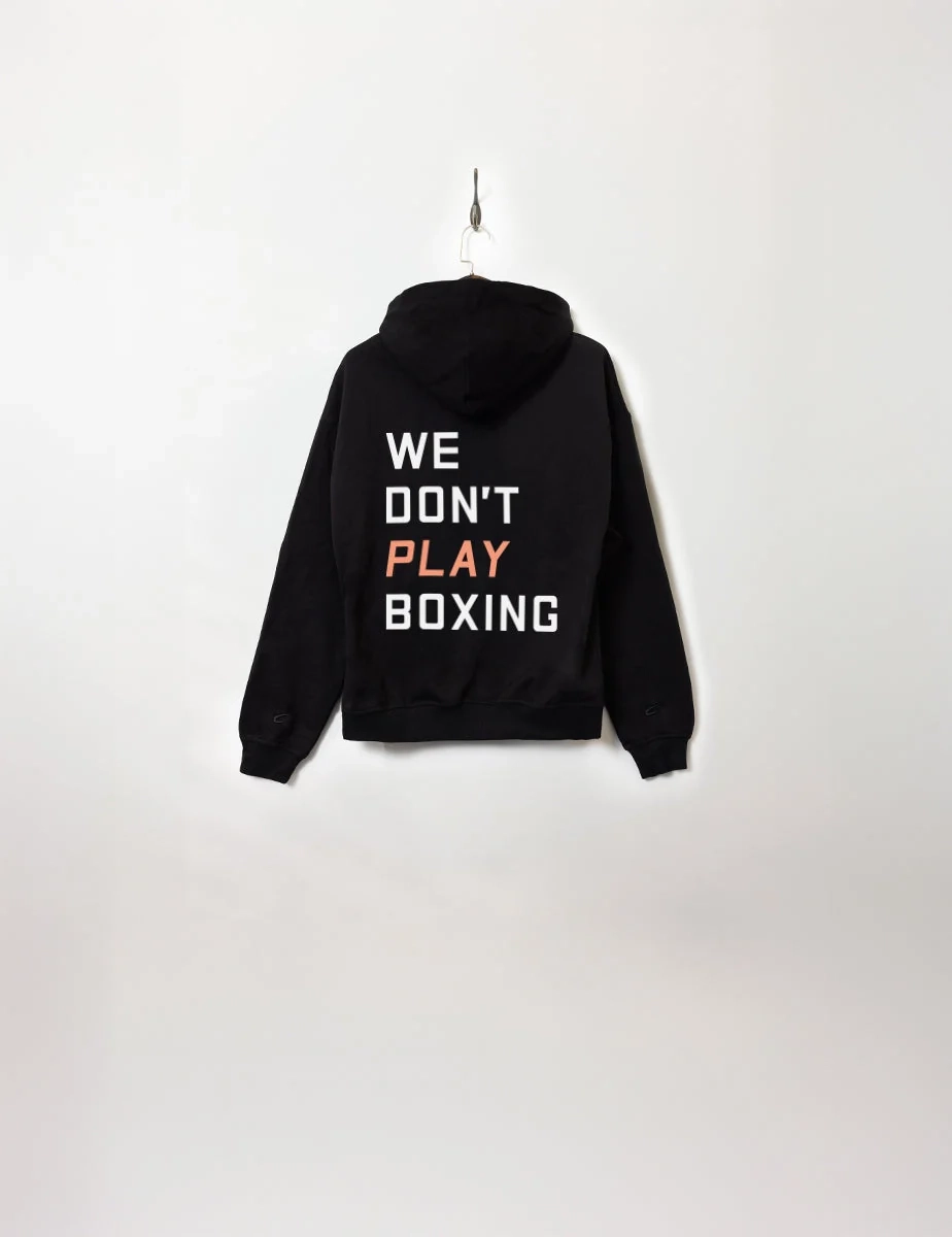 A black hoodie reading We Don't Play Boxing on a hanger