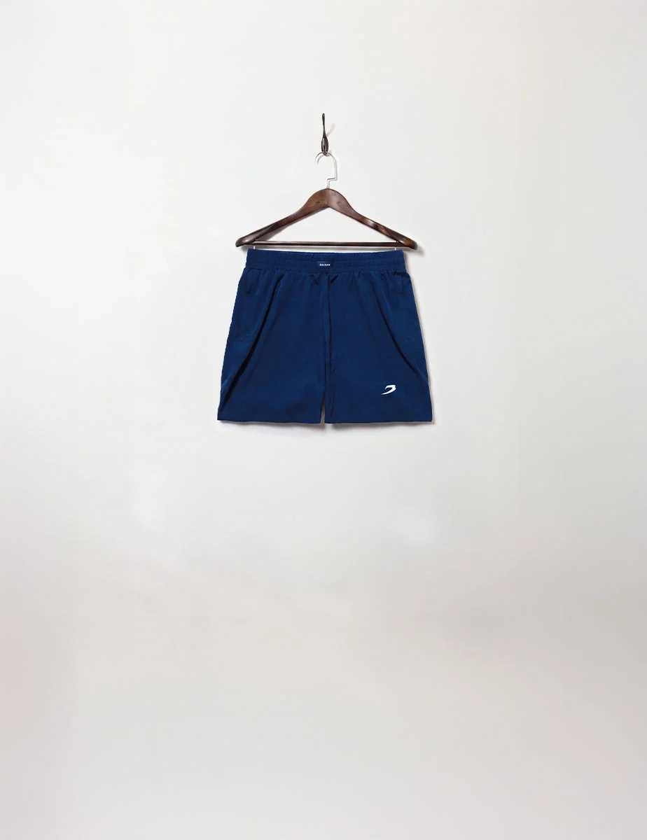 Navy blue shorts with a small BOXRAW mark on a wooden hanger