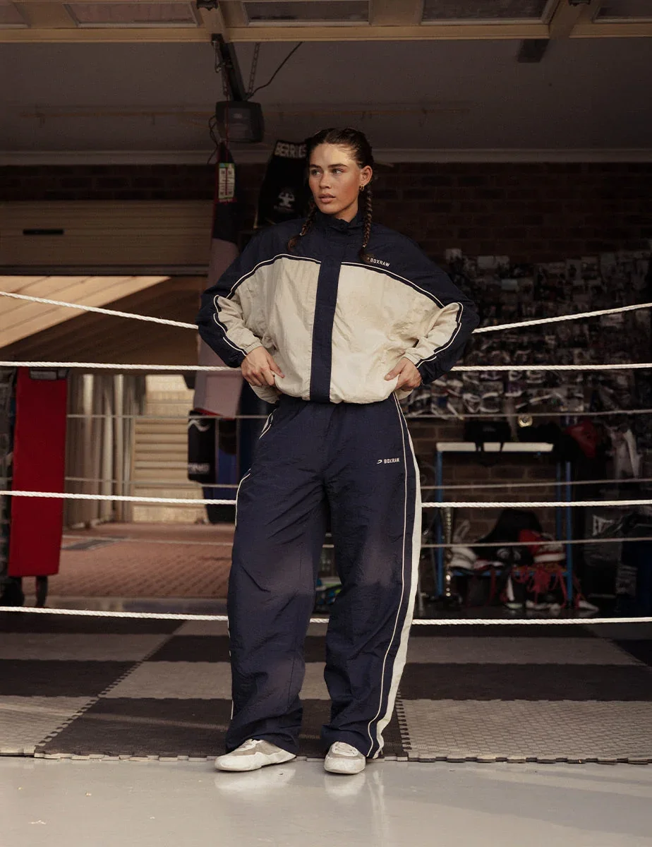 BOXRAW campaign still: a woman in a track suit standing inside the ropes